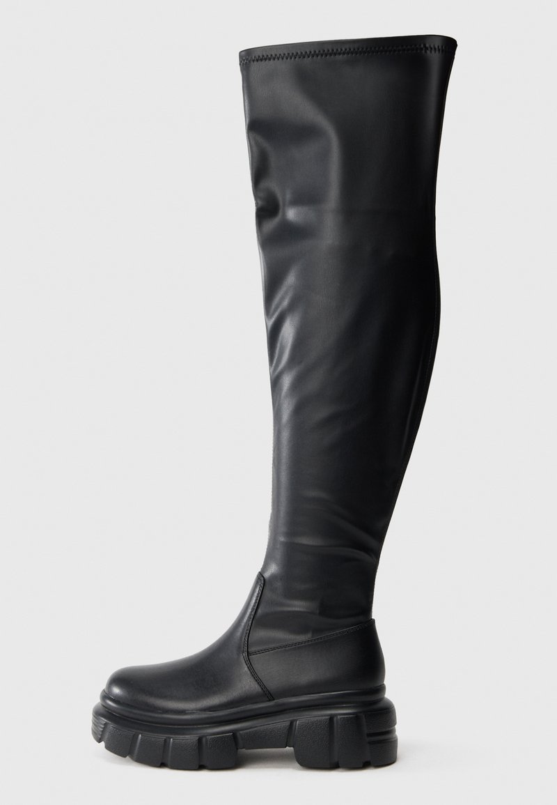 Mustad mustekad kuni põlveni, valmistatud siledast kunstnahast. Paks, tümm rubber platvormi tallaga, millel on ümar varvas ja tõmbejõud.