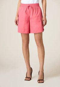 Shorts rosa, leggeri, con fascia elastica in vita e coulisse. Presentano tasche laterali e una vestibilità comoda e rilassata.