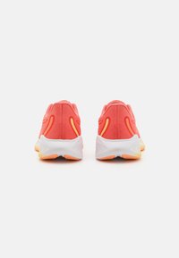 Rötlich-orange Sport Schuhe mit einem strukturierten Mesh-Obermaterial, kontrastierenden gelben Akzenten und einer weißen, gepolsterten Sohle mit orangefarbenen Details.