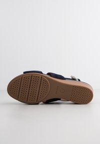 Sandały s hnědou gumovou podrážkou s kulatými vzorci a značkováním "GEOX", navy blue svršek a stříbrná spona.
