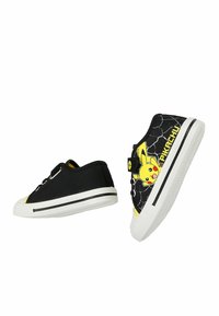 Μαύρα sneakers χαμηλού τύπου με λευκές σόλες, που έχουν γραφικό του Pikachu και σχέδιο αστραπής στη μία πλευρά του παπουτσιού, καθώς και κίτρινες λεπτομέρειες.