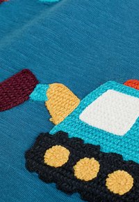 Textil mit einem blauen Hintergrund und einem strukturierten, bunten gestickten Truck-Design. Der Truck hat gelbe, schwarze und kastanienbraune Details.