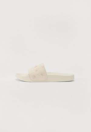 Slide sandals featuring a creamy beige upper with floral embroidery in light pink, a flat sole, and a simple, rounded design.