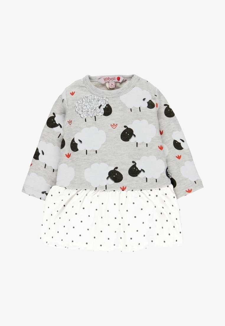Vestido gris de manga larga con estampado de ovejas en la parte superior y falda blanca con lunares, que presenta detalles en flores rojas y una cintura fruncida.