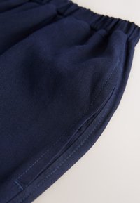 Dark navy fabric with a smooth texture, featuring an elastic waistband and side stitching details, cut in a relaxed, loose shape.
