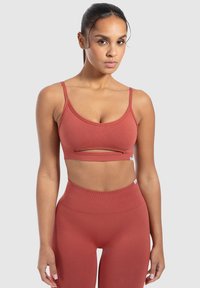 Rode ribbel sportenbh met verstelbare banden en een uitsnijding aan de voorkant, gecombineerd met hooggetailleerde bijpassende legging. Glad textuur.