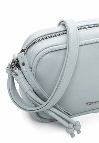 Gaiši zila ādas soma ar plecu siksnu, aizdari ar rāvējslēdzēju, pītām detaļām un sudraba rotājumiem. Gluda virsma, minimālistisks dizains.