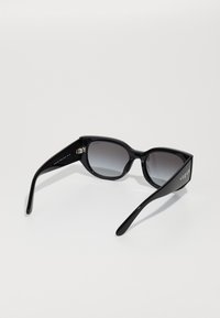 Black sunglasses with a glossy finish, rectangular lenses, and tapered arms. "Vogue" logo embossed on the temple. Gradient gray lenses.