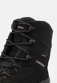 Schwarze wasserdichte Wanderschuhe mit strukturiertem Gewebe, Suede-Akzenten, verstärktem Schnürsystem und Logodetail. Mit Gore-Tex-Branding.