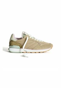 Zapatilla deportiva beige con materiales de ante y malla, cordones blancos, detalles en verde en el talón y suela de goma texturizada. Presenta la marca "HOFF".