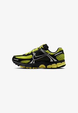 Scarpa da corsa da uomo in nero, giallo e bianco con tomaia in mesh, suola ammortizzata e logo Nike Swoosh riflettente sul lato.