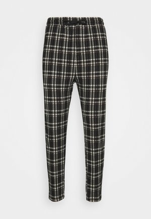 Schwarz-weiße Karo-Hosen mit einem elastischen Bund, Kordelzug und vertieftem Bein. Der Stoff hat eine strukturierte Oberfläche.