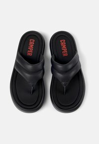 Mustat nahkaiset flip-flopit, joissa on kaksi leveää remmiä. Pehmeä pohja, jossa on teksturoitu pinta ja punainen "CAMPER"-logo pohjallisessa. Pyöristetty pohjan reuna.