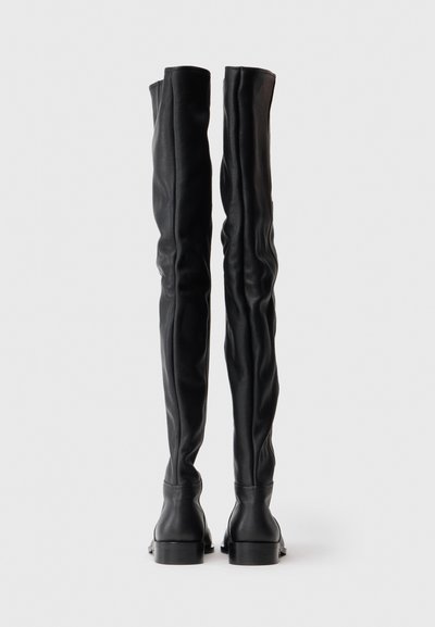 Botas de cuero negro sobre la rodilla con un diseño ajustado, superficie texturizada y un tacón grueso. Sin herrajes ni patrones visibles.