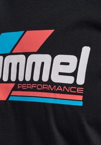 Czarna bawełniana koszulka z wyrazistym białym napisem "Simmel PERFORMANCE" oraz czerwonymi i niebieskimi akcentami geometrycznymi. Gładka faktura i swobodny styl.