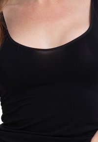 Canottiera nera in tessuto elasticizzato, con scollo ampio e texture liscia, con una leggera lucentezza visibile in determinate condizioni di illuminazione.