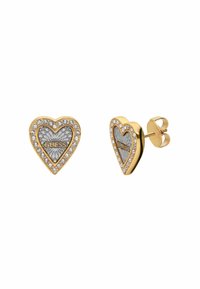 Orecchini a forma di cuore in tonalità oro con dettagli in argento, circondati da piccoli cristalli trasparenti. Presentano il logo "GUESS" in evidenza al centro.