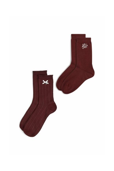 Deux paires de chaussettes rouge foncé, une paire avec une texture côtelée et un détail nœud blanc, l'autre paire unie avec des initiales blanches brodées.