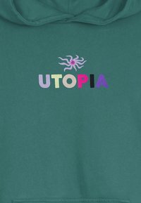 Zelená mikina s kapucňou, s vyšívaným textom "UTOPIA" v rôznych farbách a dekoratívnym vzorom vír nad ním. Mäkko šitý materiál s textúrovaným povrchom.