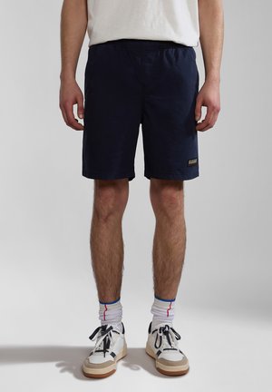 Navy shorts made of lightweight material, featuring an elastic waistband, side pockets, and a small logo patch on the left thigh.