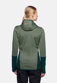 Kapuzenshirt in Dunkelgrün mit kontrastierenden grünen Seitenteilen, einer strukturierten Oberfläche und langen Ärmeln, entworfen für Komfort und Flexibilität.