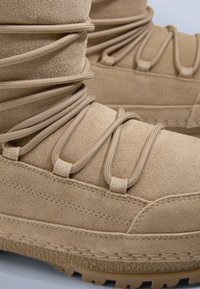 Beige mockastövlar med strukturerad ovandel, med fina snörningsdetaljer och kraftig gummisula, designade för hållbarhet och grepp.