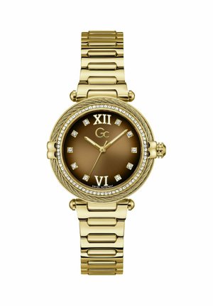 Reloj de pulsera tono dorado con esfera marrón, marcadores de hora de cristal, números romanos en las posiciones 12 y 6, y una correa metálica estilo pulsera.