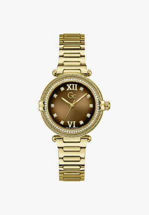 Kullavärvi käekell pruunika sihverplaadiga, kristallist tunniindeksid, rooma numbrid kell 12 ja 6 juures ning käevõrusti stiilis metallist rihm.