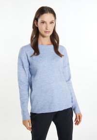 Lichtblauwe trui met een textuurafwerking, ronde hals en geribbelde manchetten. Losse pasvorm en iets cropped zoom, gecombineerd met donkere broek.