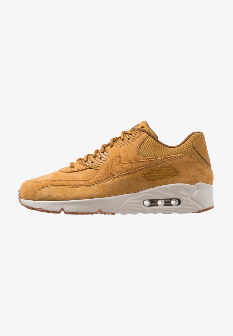 Baskets Nike Air Max en daim beige avec coussin d’air visible dans la semelle blanche, design à lacets et détails en tissu texturé au talon et à la languette.
