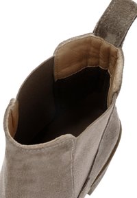 Stivale alla caviglia in suede marrone con una texture liscia e una punta rotonda. Presenta un rivestimento in morbida pelle e un manico sul retro per una facile vestibilità.