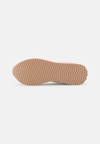 Suela de zapatilla con una base de goma texturizada y un patrón de espiga en marrón claro, que proporciona agarre y durabilidad.