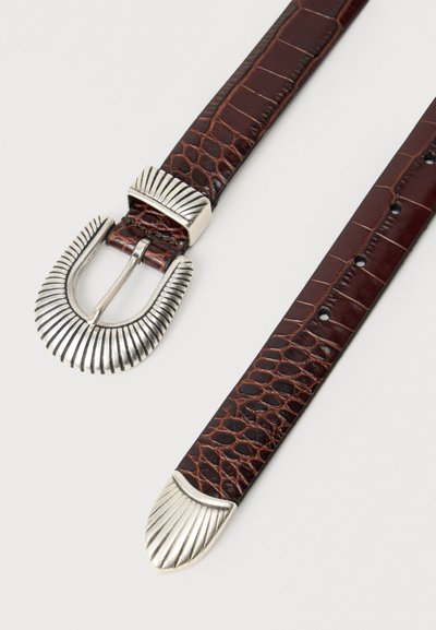 Ceinture en cuir brun foncé à motif crocodile avec boucle, passant et extrémité argentés rainurés, posée à plat sur fond blanc.