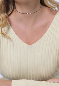Black choker necklace with three small silver beads, featuring a simple, smooth design. Worn with a ribbed, cream-colored top.