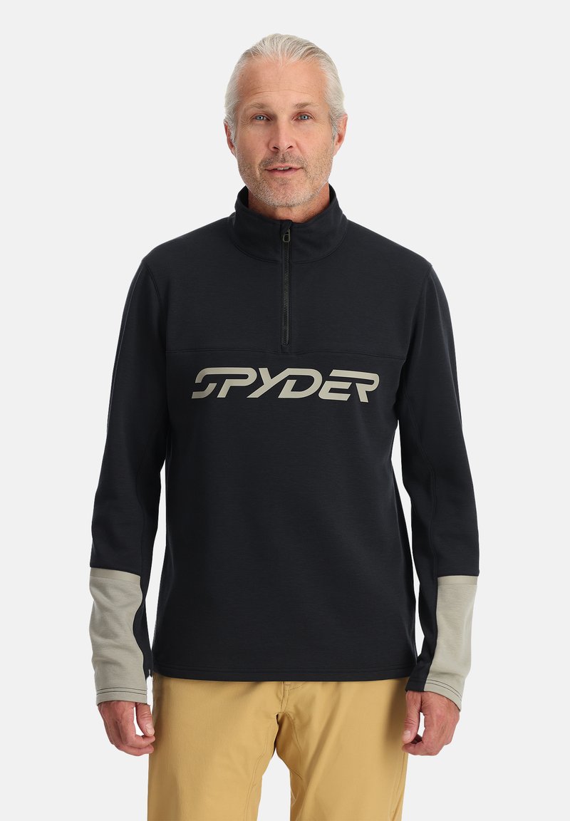 Maglione nero con colletto alto e zip a quarti. Presenta un grande logo bianco "SPYDER" sul petto e dettagli grigi sulle maniche. Texture morbida.