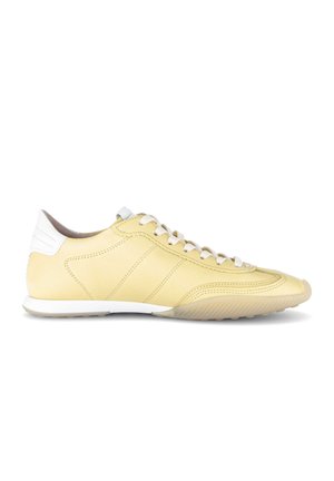 Gele leren sneaker met witte veters en hielriempje, lage zool en gestikte paneel details, gezien van opzij.