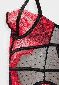 Rød og svart blonde-lingeri med gjennomsiktig polka dot mesh, intrikate blomstermønstre og sorte stropper som fremhever kontrasterende sekjoner.
