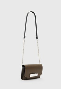 Brun læder crossbody taske med flaplukning, sølv hardware og en lang sort kædeder. Glat tekstur, minimalistisk design.