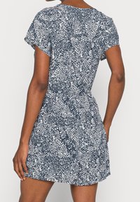 Short-sleeve dress featuring a navy and white abstract pattern, soft fabric, relaxed fit, cinched waist, above-knee length.