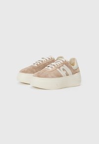 Beige semskinn-sneakers med en kraftig hvit såle, snøring og en fremtredende beige logo på siden. Glatte skinnapplikasjoner på hælen.