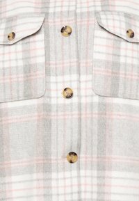 Grå og hvid ternet skjorte med lyserøde striber, to brystlommer og runde knapper med skildpaddemønster. Blød tekstur.