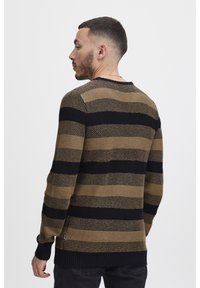 Maglione a righe con lavorazione a maglia texture in marrone e nero. Collo a giro, polsini e orlo a costine. Indossato da un'angolazione posteriore.