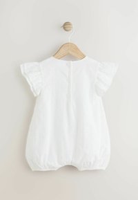 Romper blanc avec des manches volantes, doté d'une fermeture à boutons à l'arrière et d'un motif en œillets texturé sur l'ensemble. Tissu doux et respirant.