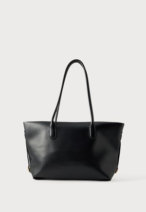 Sac cabas en cuir noir avec deux longues anses et une surface lisse et unie, présenté sur un fond clair uniforme.
