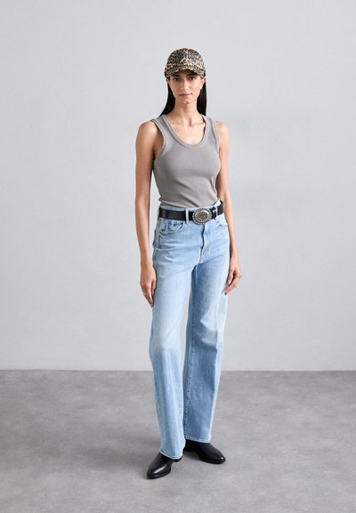 Gray ribbed tank top, light blue straight-leg jeans, black belt with circular buckle, and leopard print cap. Black pointed-toe ankle boots.