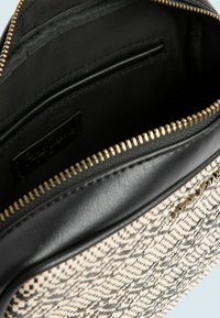 Borsa con zip superiore in tessuto intrecciato beige e nero, rifiniture in pelle nera, zipper dorato e tasca interna a soffietto. Texture liscia.