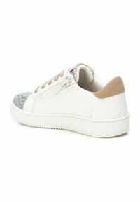 Zapatilla blanca con punta en purpurina plateada, acento en talón de ante beige y cordones beige. Presenta un zipper lateral para facilitar su uso.