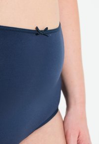 Mutande in cotone blu navy a vita alta, caratterizzate da una texture liscia, un dettaglio a fiocco decorativo sulla vita e una vestibilità aderente.