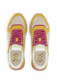 Baskets avec un dessus en daim jaune et en mesh beige, des lacets roses pailletés, un logo blanc et une semelle multicolore avec des accents roses.