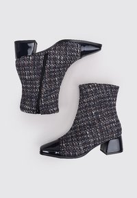 Botas de tobillo texturizadas hechas de tela tejida en color azul marino con motas multicolores, que cuentan con una punta de charol negro brillante y un diseño de tacón cuadrado.